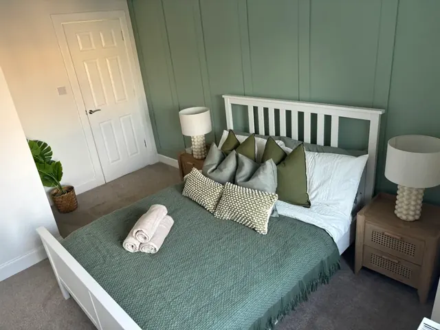 Double bed with fresh white linen, rolled towels and bedside lamps
