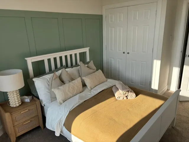 Second double bedroom with mustard throw and wooden bedside tables